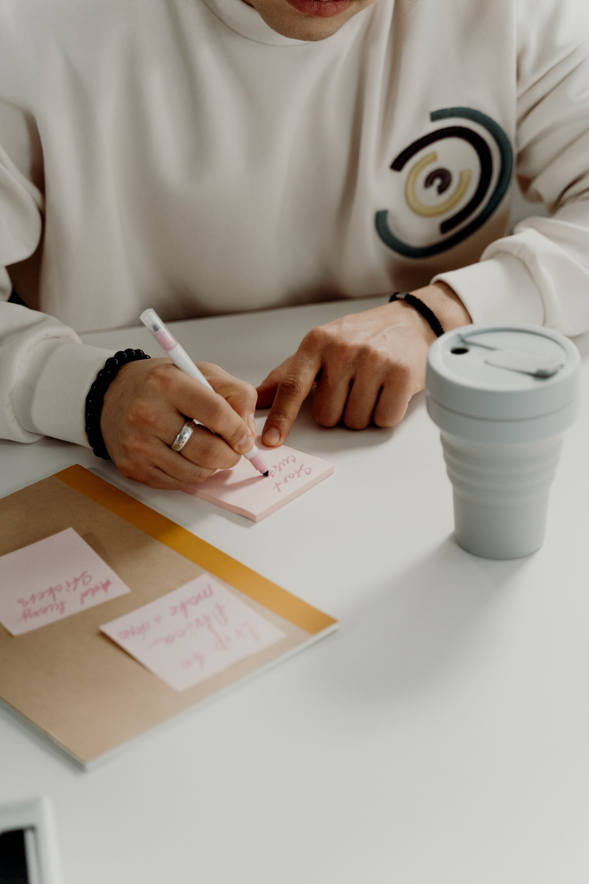 Person in White Long Sleeve Shirt Writing on a Sticky Note